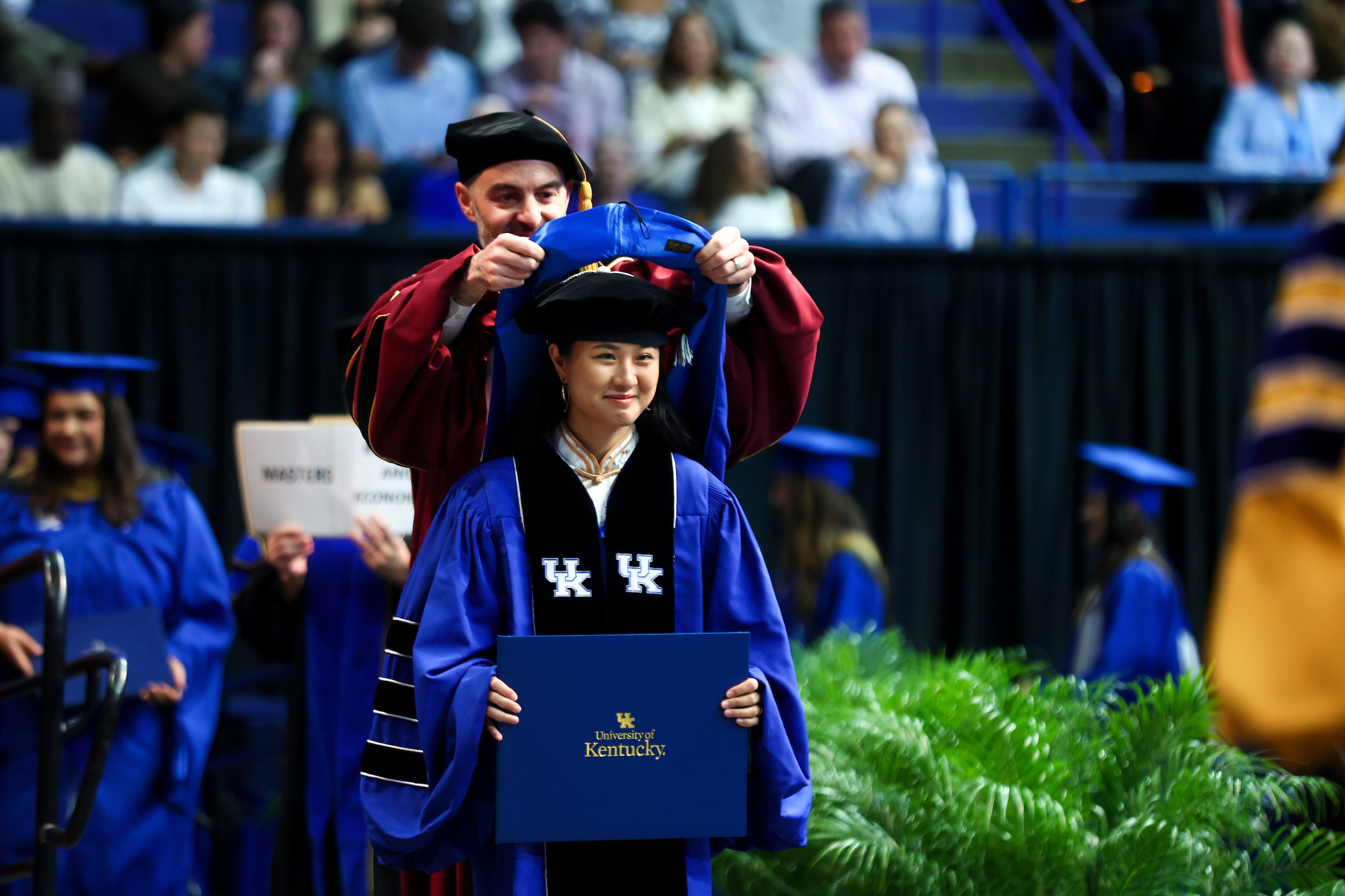 doctoral student on stage hood ceremony graduation