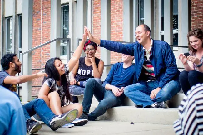 college of education graduate students smiling on stairs high fiving