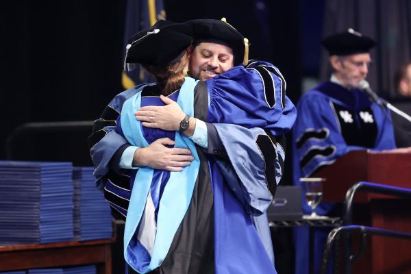 doctoral student on stage hood ceremony graduation