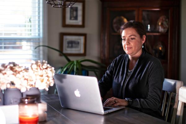 woman sitting at laptop desk at home with candle and flowers