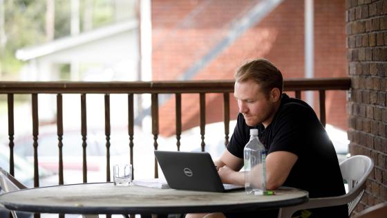 student working outside on laptop in shorts