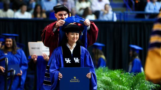 doctoral student on stage hood ceremony graduation
