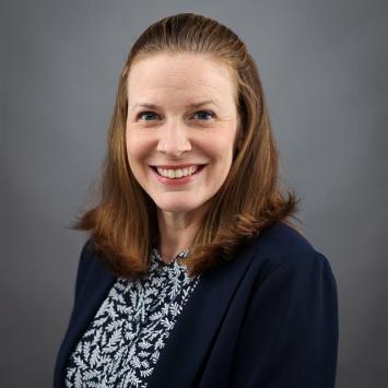 Brandi Frisby posing for a portrait wearing a navy blue cardigan.