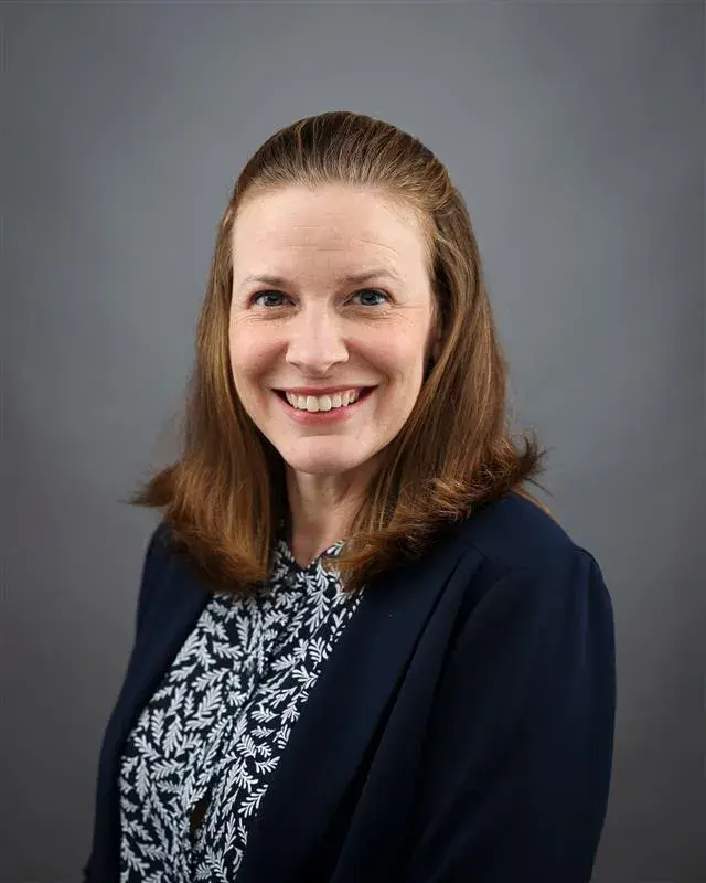 Brandi Frisby posing for a portrait wearing a navy blue cardigan.