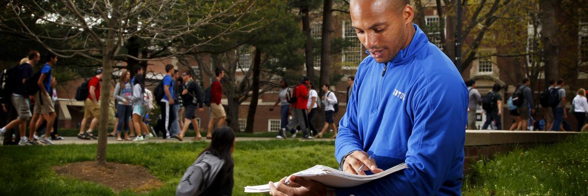 student on campus looking at notes and smiling