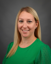 headshot of tammy anding green shirt grey background smiling